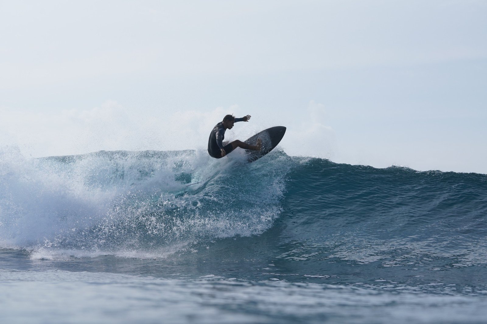 Surfer performing an aerial manoeuvre above a wave