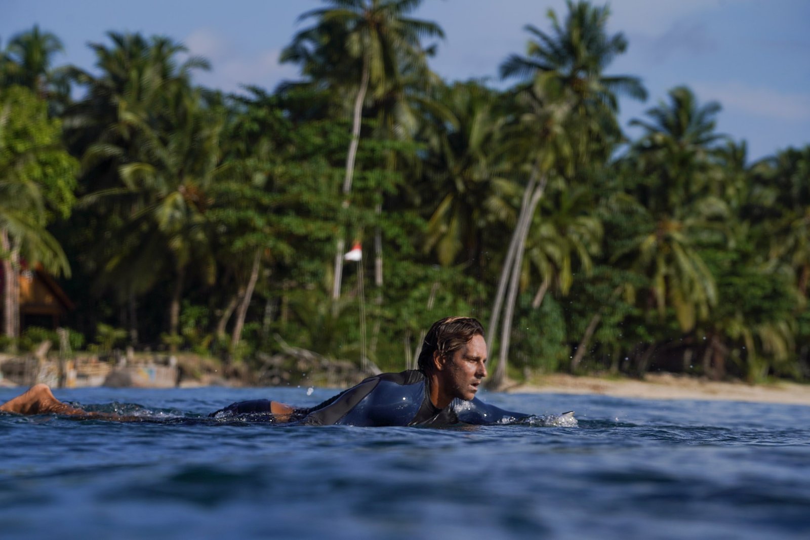 Surfer paddling in the ocean near a tropical island